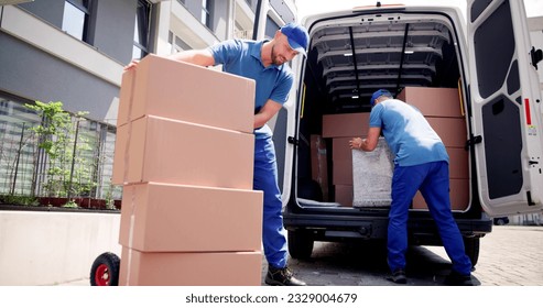 Two Young Male Movers Carrying Cardboard Box From Truck - Powered by Shutterstock