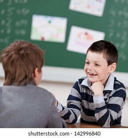 Two Young Male Students Talking In The Classroom