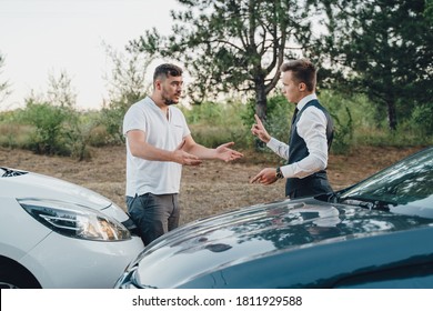 two Young Man Arguing With Each Other After Car Accident On Street At Outdoors. no one wants to give way to each other. Men argue and sweat. Two drivers quarreling and gesturing on road 