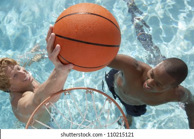 Two young man playing water basketball in swimming pool - Powered by Shutterstock