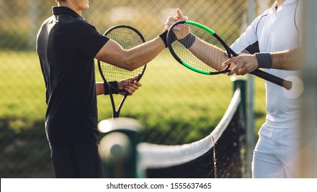 Two young man shaking hands after playing tennis. Tennis players shaking hands over the net after the match. - Powered by Shutterstock