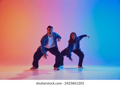 Two young man and woman, contemp dancers in urban style outfit performing in motion against gradient studio background in neon light, filter. Concept of youth culture, music, lifestyle, fashion. Ad - Powered by Shutterstock