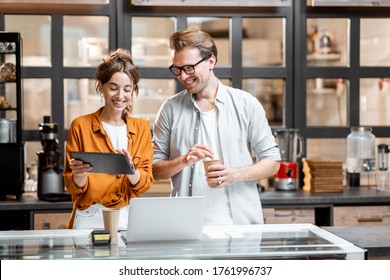 Two young managers or shop owners having some discussion while standing with a digital tablet at the counter of the shop or cafe. Small business management concept - Powered by Shutterstock