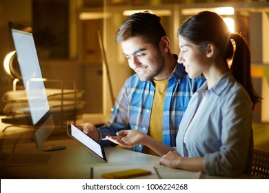 Two young managers with tablet sitting by desk and discussing data for new project in office at night - Shutterstock ID 1006224268