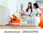 Two young medical students in white coats are closely examining a human anatomical model within a classroom setting, focusing on the anatomy of the human body.