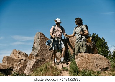 Two young men, a gay couple, hike rocky terrain on a sunny day. They carry backpacks and hiking poles. - Powered by Shutterstock