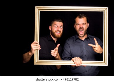 two young men posing happy on black background with gold frame photo booth