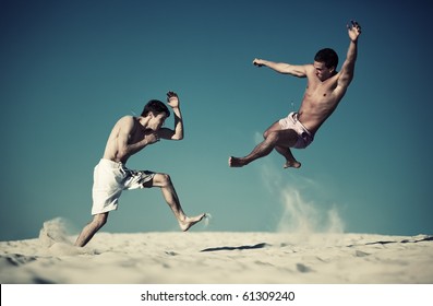 Two Young Men Sport Fighting On Beach. Yellow And Blue Contrast Colors.