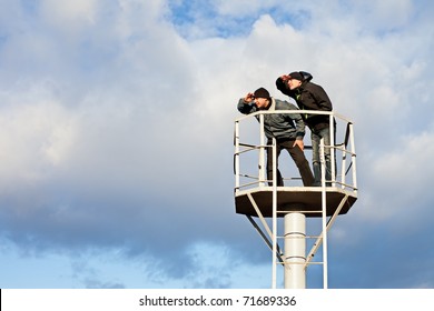 Two young men standing on tower against sky. Looking into distance
