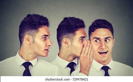Two young men whispering each other and to astonished guy in the ear. Word of mouth concept 