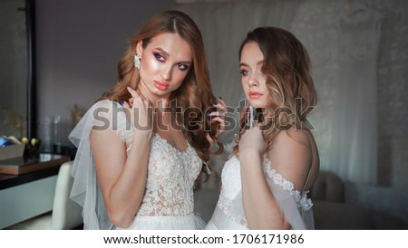 Two young models posing in front of the photographer in a wedding dress.