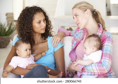 Two Young Mothers On Sofa At Home