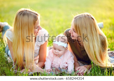 Two young mothers are walking in the park in summer with her baby. LGBT Lesbian Couple. The concept of  family and healthy lifestyle