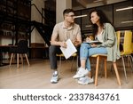 Two young multiethnic students preparing for exams together while sitting in university library