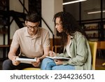 Two young multiethnic students preparing for exams together while sitting in university library