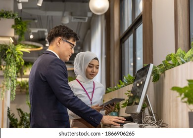 Two young office workers are using computer and digital device or smart technology as part of their business in an environmental friendly office. Technology for smart business - Powered by Shutterstock