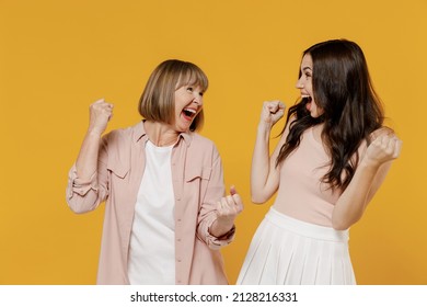 Two young overjoyed excited fun daughter mother together couple women in casual beige clothes do winner gesture clench fist isolated on plain yellow background studio portrait Family lifestyle concept - Powered by Shutterstock