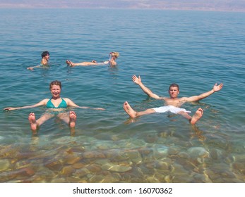 Two Young People Floating In The Dead Sea Water