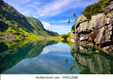 Two young people have fun and jumping together to the clear lake in mountains. Photo from nature  full of entertaintment and happiness. With joy, space for your montage  - Shutterstock ID 549212080