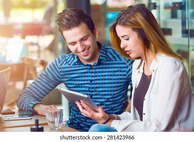 Two Young People, Man And Woman, Looking At A Tablet