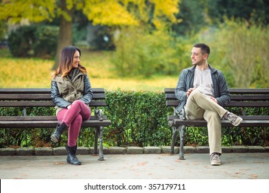 Zwei junge Leute sitzen auf Bänken im Park und reden