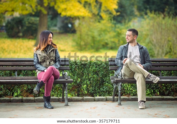 公園のベンチに座って話をする2人の若者 の写真素材 今すぐ編集