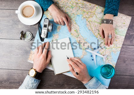 Two young people together planning trip to Europe. Top view. empty white space in notebook where you can place your text or advertisement.  Romantic travel