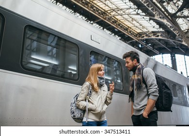 Two young people tourists standing at the railway station and talking.