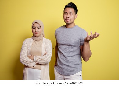 Two Young People, A Woman Hijab And A Man With An Expression Asking Something. Isolated On Yellow Background