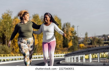 Two young plus size women jogging together on road. - Powered by Shutterstock