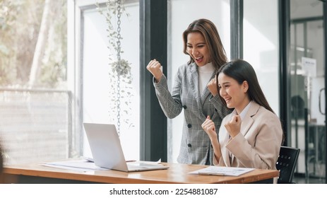 Two young pretty asia business woman in suit talking together in modern office workplace, Thai woman, southeast asian, looking on laptop together - Shutterstock ID 2254881087
