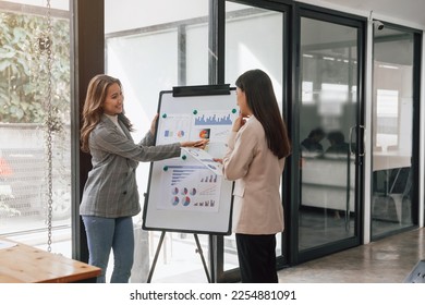 Two young pretty asia business woman in suit talking together in modern office workplace, Thai woman, southeast asian, Standing over whiteboard, presenting - Shutterstock ID 2254881091