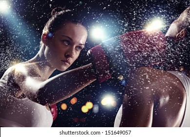 Two young pretty women boxing standing against flashes background - Powered by Shutterstock