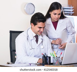 Two Young Professional Doctors Brainstorming And Sharing Information In Clinic