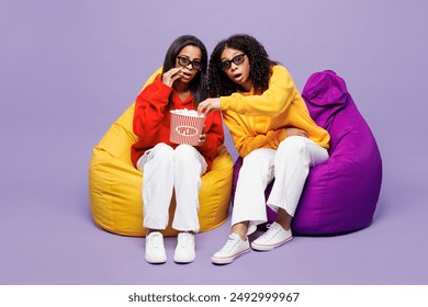 Two young sad little kid teen girls women they wear red yellow hoodie casual clothes 3d glasses sit in bag chair watch movie film hold bucket of popcorn in cinema isolated on plain purple background - Powered by Shutterstock