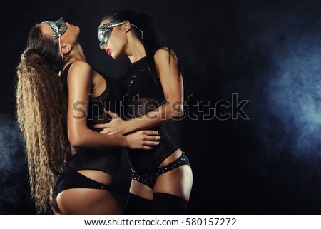 two young sexy striptease dancer with mask, dark background with smoke