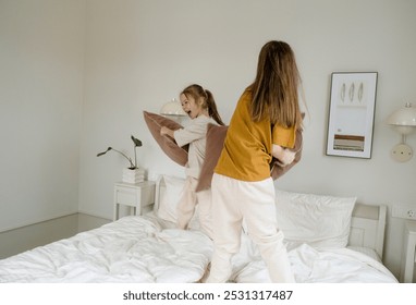 Two young sisters are having a pillow fight on a bed, their laughter echoing through the room. They re clearly enjoying their playful battle, showcasing the joy of sibling rivalry and the lighthearted - Powered by Shutterstock