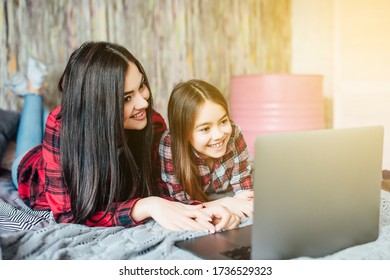 Zwei junge Teenagerschwestern, die mit Laptop ins Kino schauen, wohnen zu Hause im Schlafzimmer.