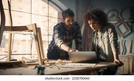 Two Young Small Business Owners Using Laptop Computer and Discussing the Design of a New Wooden Chair in a Furniture Workshop. Carpenter and a Young Female Apprentice Working in Loft Studio. - Powered by Shutterstock