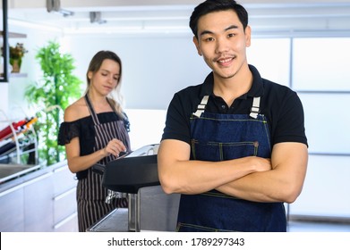 Two Young Smiling Barista At Work. Professional Barista Team Brewing Coffee Using Coffee Machine In Coffee Shop. Happy Young Man And Woman Developing Own Coffee Business.