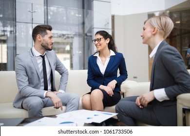 Two Young Smiling Caucasian Women And One Man At A Business Meeting In The Business Center