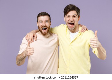 Two young smiling cheerful positive cool men friends together in casual t-shirt tattoo translate fun show thumbs up gesture isolated on purple color background studio portrait People lifestyle concept - Shutterstock ID 2011284587