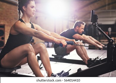 Two young sportsmen having hard workout on rowing machines in gym.  - Powered by Shutterstock