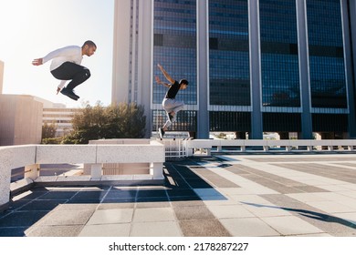 Two young sportsmen practicing parkour against a city background. Young people practicing extreme sport activities outdoors in city. Male athletes running and jumping over obstacles. - Powered by Shutterstock