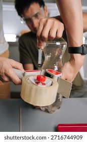 Two young student preparing liquid fertilizer in plastic bottle, using syringe and tape dispenser for science experiment in laboratory. Concept of sustainable innovative approach to indoor gardening.