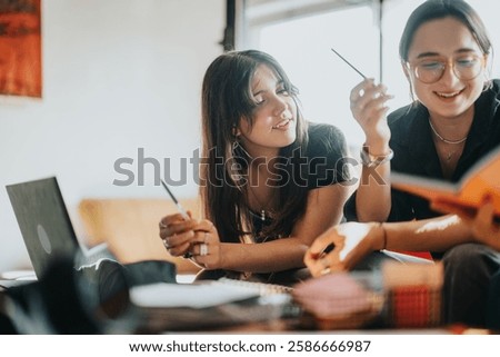 Two young students joyfully working together on school tasks, using a laptop and books. The atmosphere is casual and collaborative, fostering a positive learning experience.