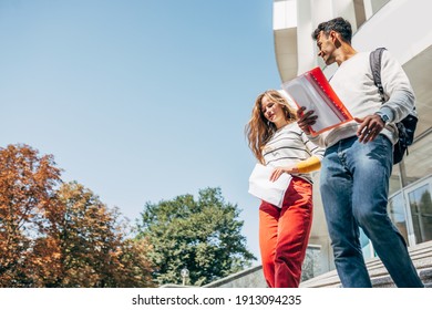 Two Young Students Talking To Each Other During Descend The Stairs At The University Outside. Two Colleagues Smiling, A Young Woman And A Man Going To The College Campus Together.