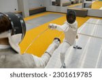 Two young swordsmen in uniform practicing attack and defense during training