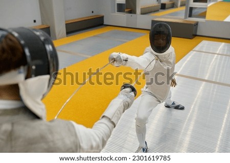 Two young swordsmen in uniform practicing attack and defense during training