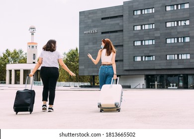 two young tourists wearing masks walk to their hotel maintaining a safe distance due to covid-19 - Shutterstock ID 1813665502